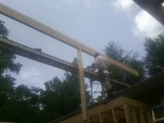 Carpenter setting a ridge beam over a new addition frame — Ice Dam Removal by Roofing Brothers in Huntingtown