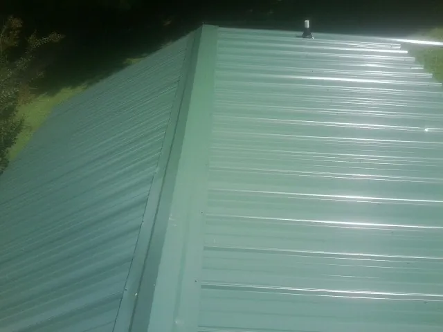 New green metal panels meeting at the ridge of a roof — Flat Roof Repair work by our crew in Huntingtown
