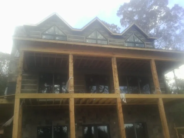 Dormers and porch framing on a large log home under construction — Roof Coating work by our crew in Huntingtown