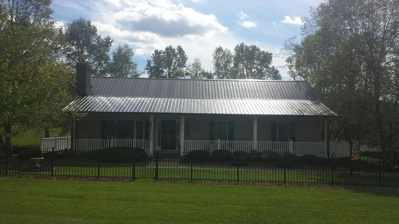 Gray metal roof on a brick ranch with a full width front porch — Gutter Guard Installation work by our crew in Huntingtown