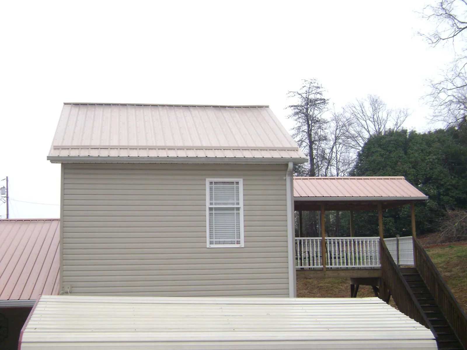 Tan metal roofs on a two story addition and attached porch, from a Roof Replacement job in Huntingtown