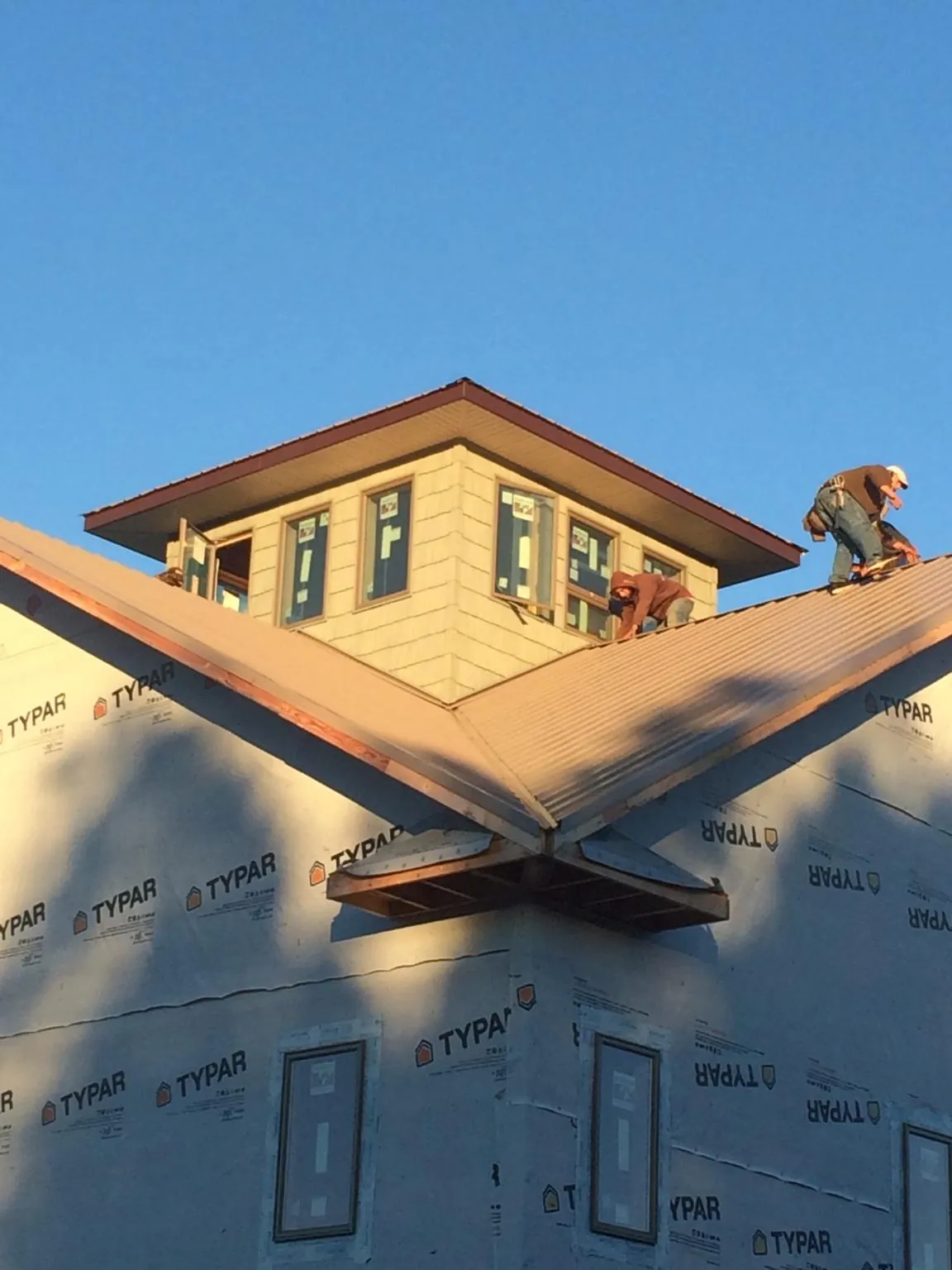 Roofers working around a rooftop cupola on a new metal roof at sunset — Roof Waterproofing in Huntingtown by Roofing Brothers